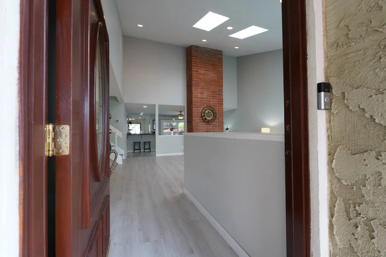 View through the front door toward skylights and the brick fireplace chimney
