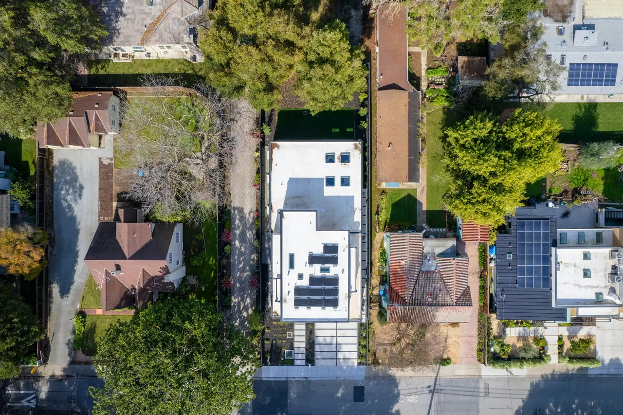 Top-down aerial view of the roof, solar panels, and backyard