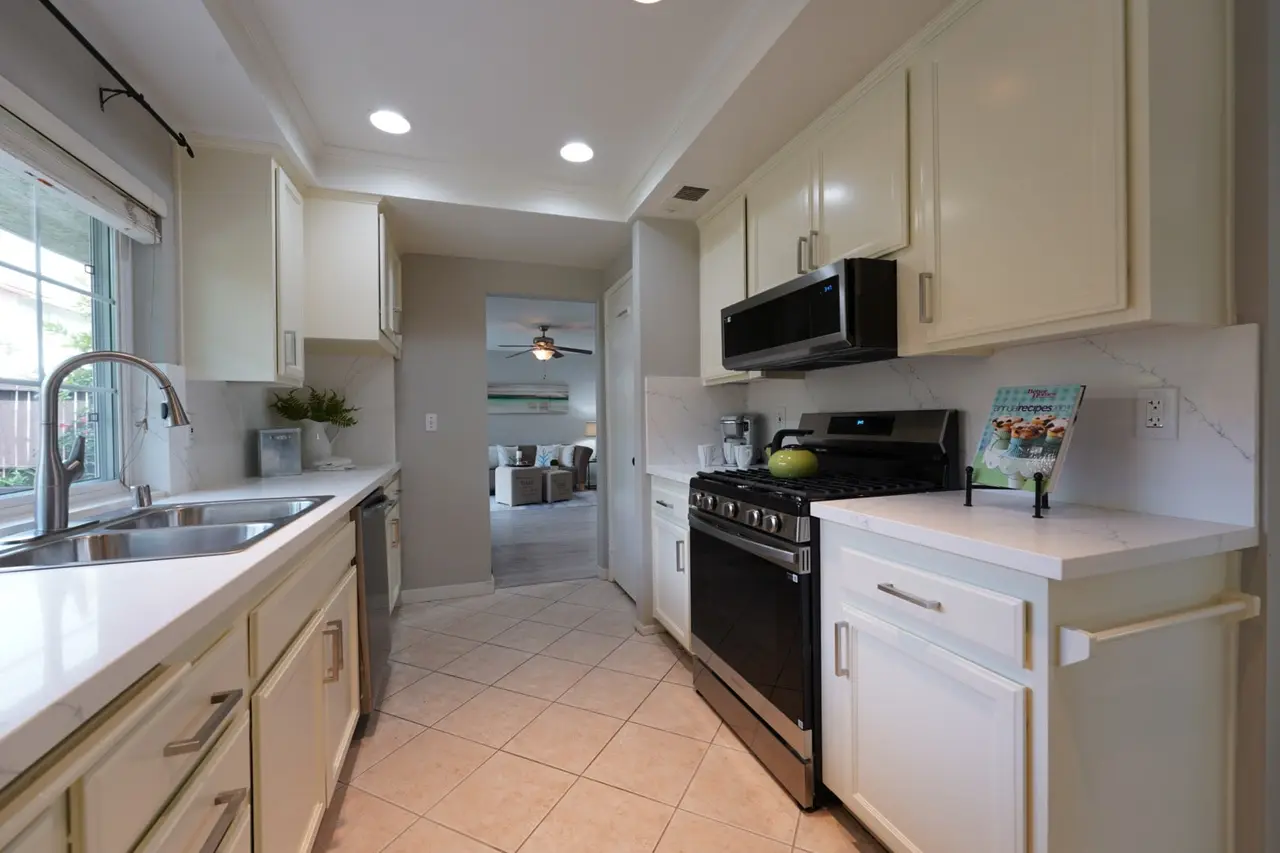 Kitchen with white cabinets, a gas range, and a window over the sink