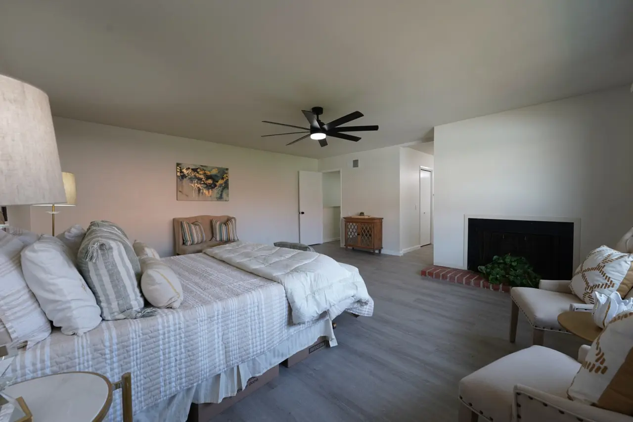 Primary bedroom with a fireplace and a ceiling fan