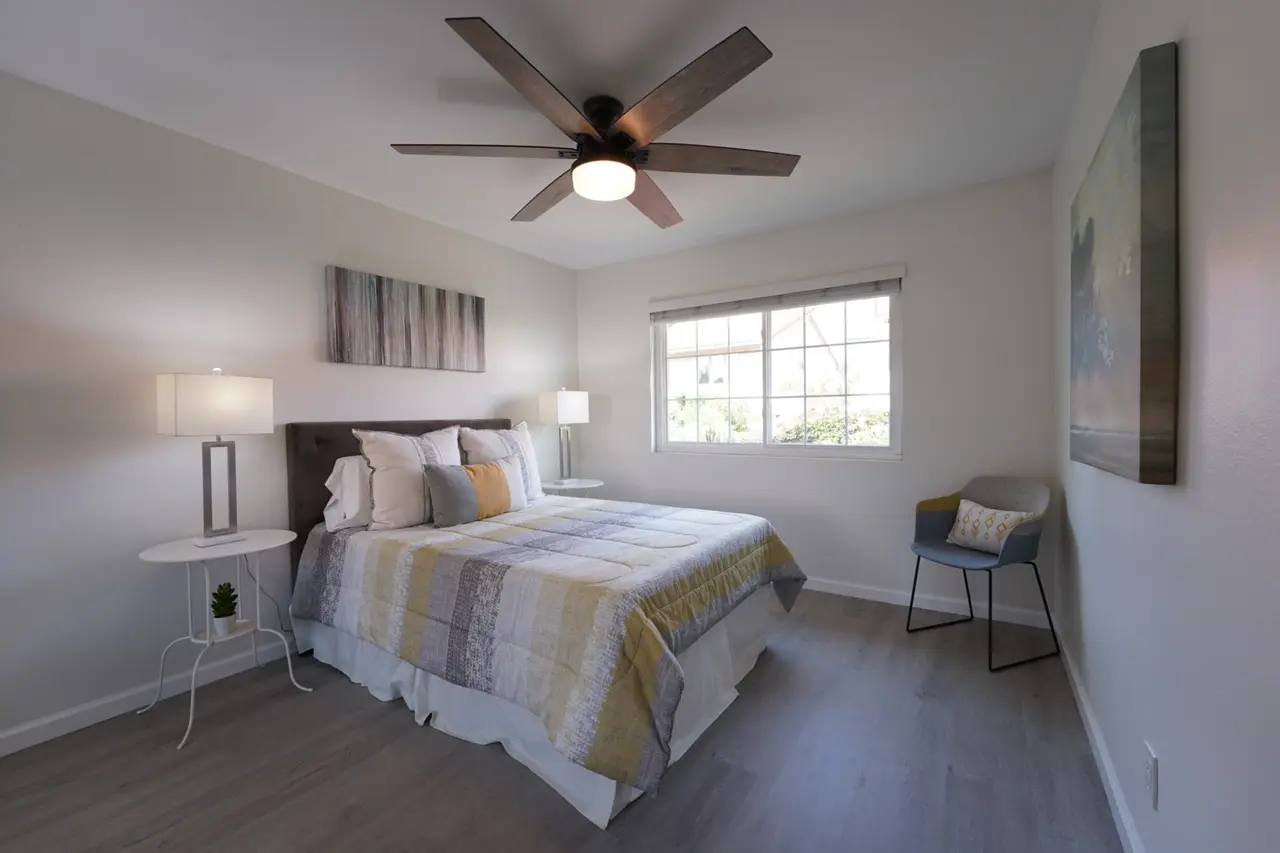 Bedroom with a ceiling fan and a window facing the bed