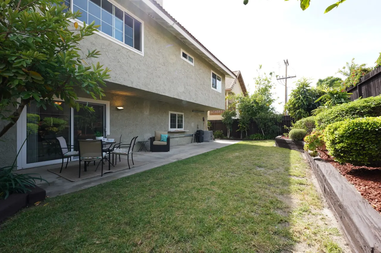 Backyard lawn with a patio and terraced planters along the fence